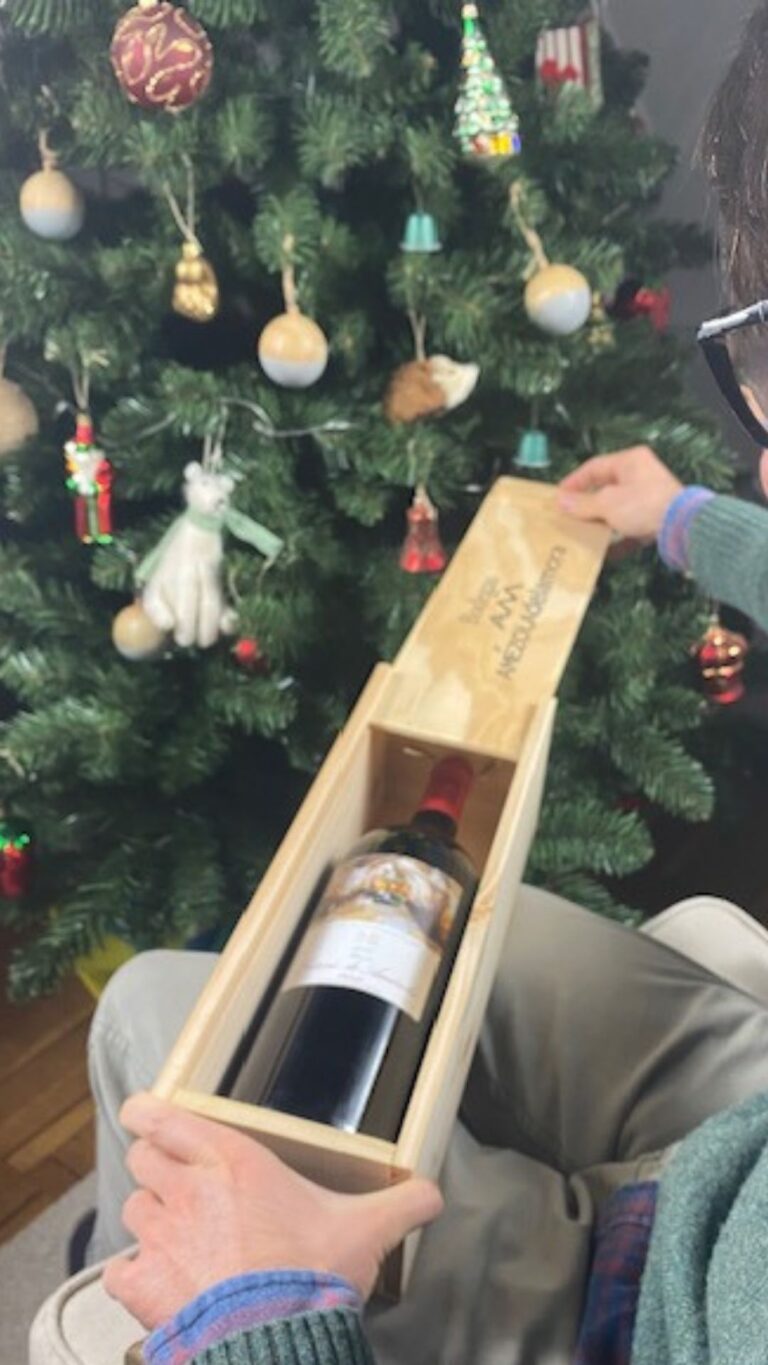 botella de crianza en una caja de madera con fondo de arbol de navidad